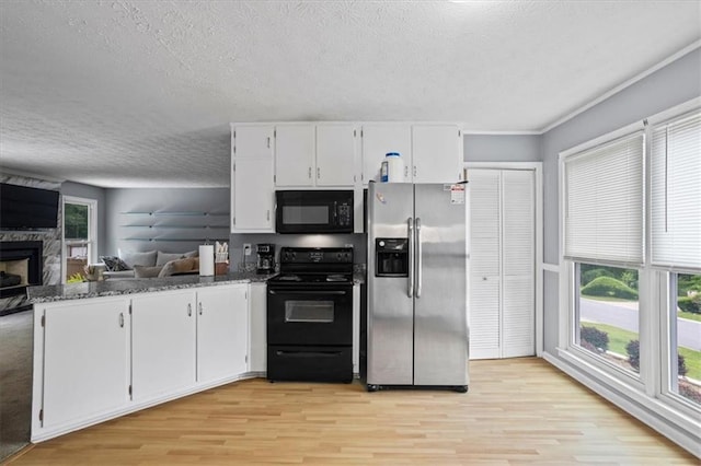 2711 Bluffton Rd, Buford, GA 30519 - kitchen featuring black appliances, light wood-style flooring, a textured ceiling, white cabinets, and a high end fireplace