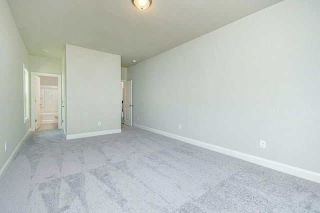 unfurnished bedroom with light carpet, baseboards, and connected bathroom