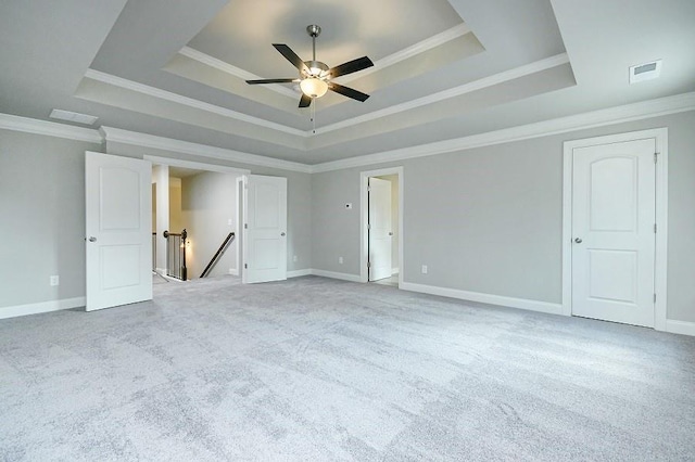 unfurnished bedroom with a tray ceiling, carpet flooring, crown molding, baseboards, and ceiling fan
