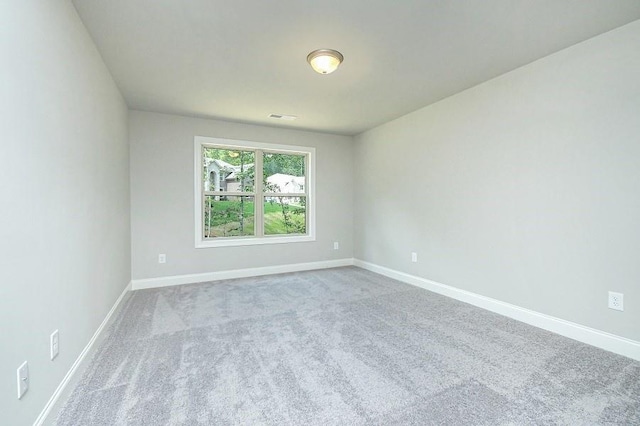 spare room featuring carpet floors and baseboards