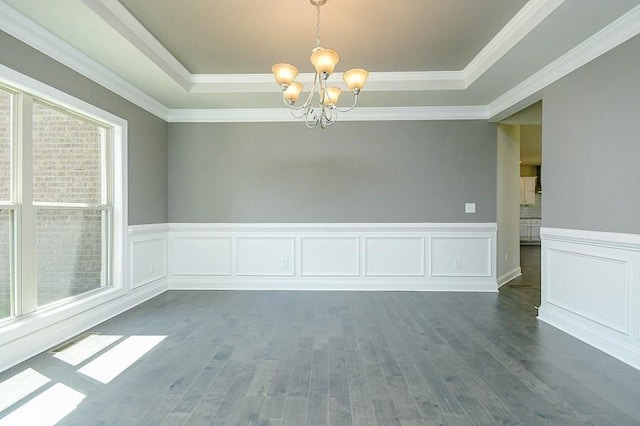 unfurnished room with a chandelier, a raised ceiling, dark wood-style flooring, a wainscoted wall, and ornamental molding