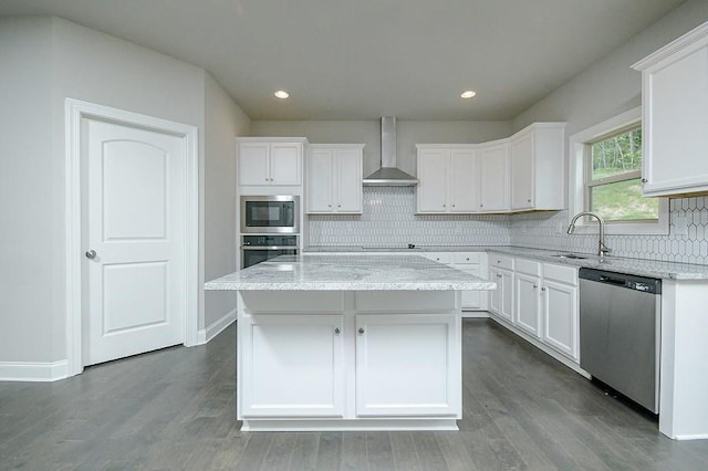 kitchen with stainless steel appliances, wall chimney range hood, a sink, white cabinets, and recessed lighting