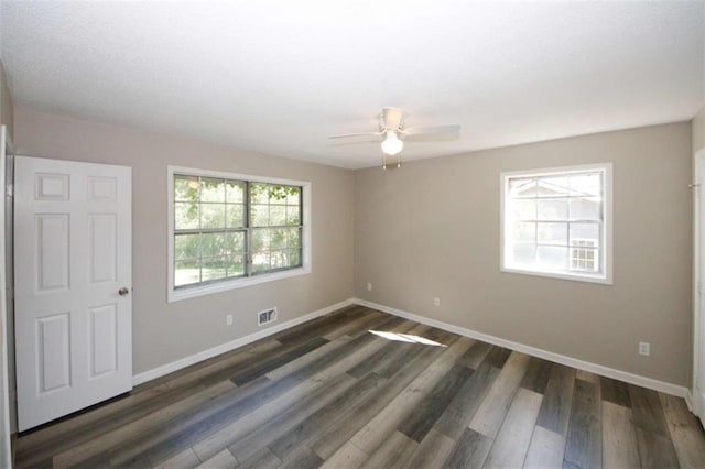 empty room with ceiling fan and dark hardwood / wood-style flooring