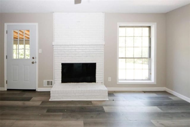 unfurnished living room featuring a fireplace, dark hardwood / wood-style floors, and a wealth of natural light