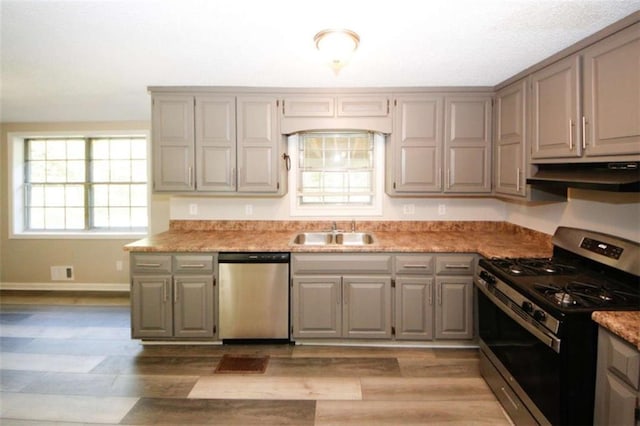 kitchen featuring light stone counters, sink, stainless steel appliances, and light wood-type flooring