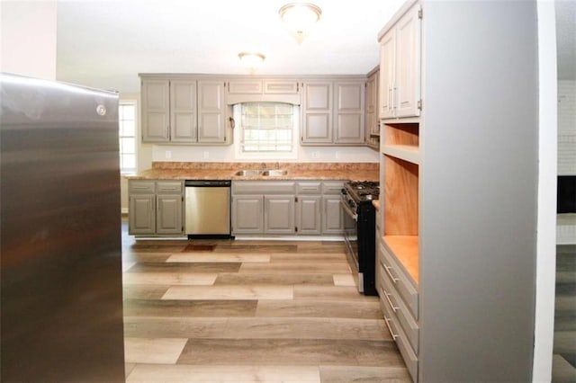 kitchen featuring light wood-type flooring, stainless steel appliances, gray cabinetry, and sink