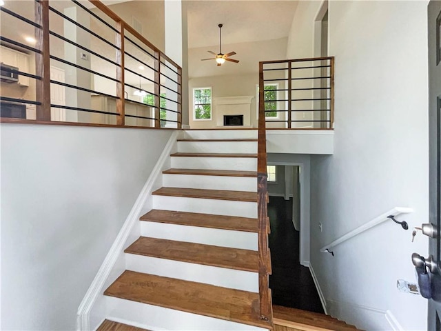 stairway with baseboards, ceiling fan, visible vents, and a high ceiling