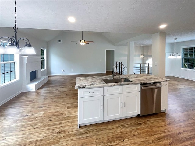 kitchen with a sink, a textured ceiling, dishwasher, and open floor plan
