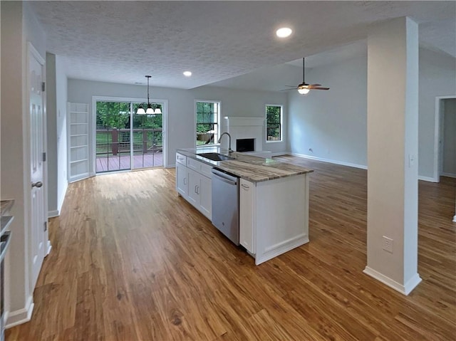 kitchen featuring a sink, a fireplace, ceiling fan with notable chandelier, white cabinetry, and stainless steel dishwasher