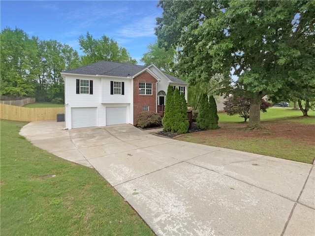 split foyer home featuring fence, a front lawn, brick siding, a garage, and concrete driveway