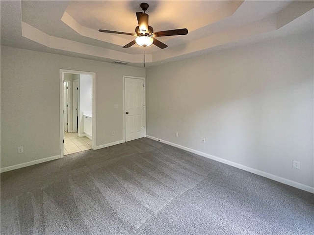 spare room featuring ceiling fan, a raised ceiling, carpet, baseboards, and visible vents