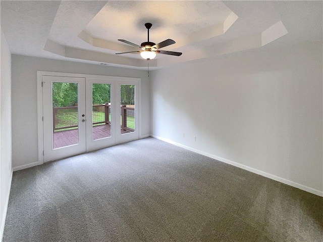carpeted spare room with a raised ceiling, baseboards, french doors, and ceiling fan