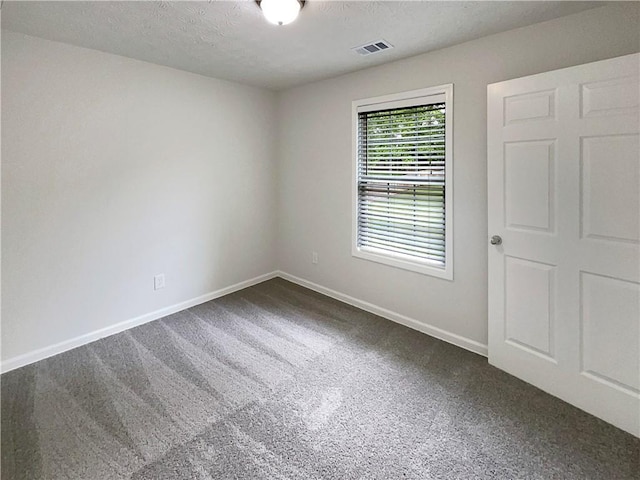 unfurnished room with visible vents, a textured ceiling, carpet, and baseboards