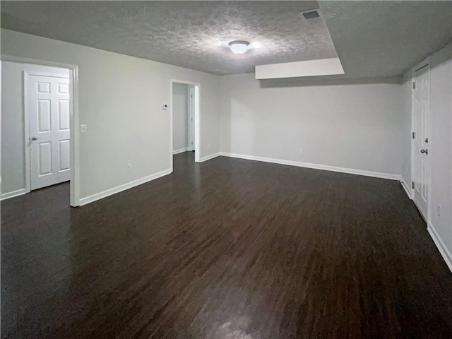 spare room featuring a textured ceiling, baseboards, and dark wood-type flooring