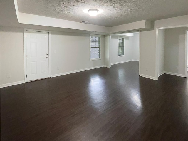 empty room featuring baseboards, dark wood-style flooring, and a textured ceiling