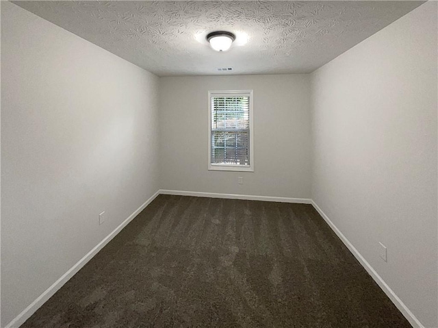 unfurnished room featuring dark carpet, a textured ceiling, and baseboards
