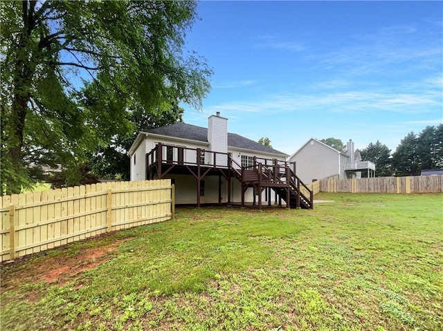 rear view of house featuring a deck, a fenced backyard, a chimney, a yard, and stairway