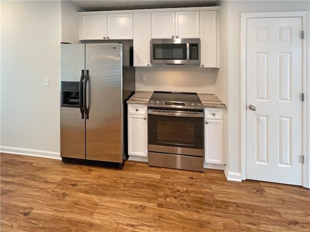 kitchen featuring wood finished floors, baseboards, light countertops, white cabinets, and appliances with stainless steel finishes