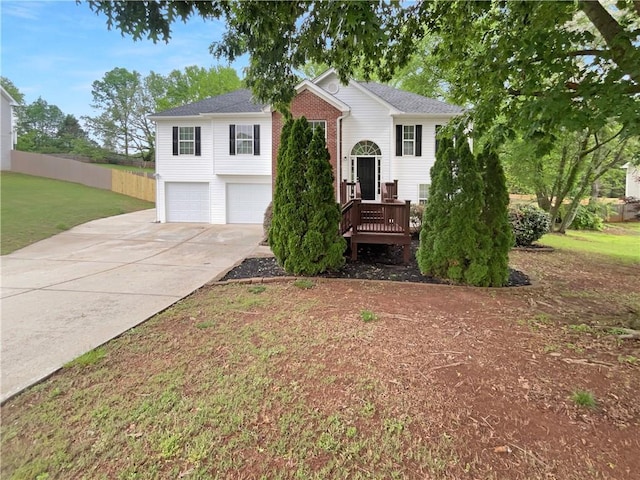 bi-level home with a garage, fence, driveway, and a front yard