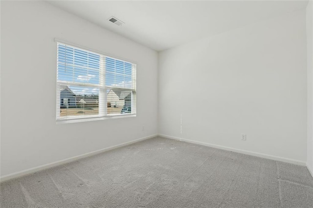 carpeted spare room featuring visible vents and baseboards