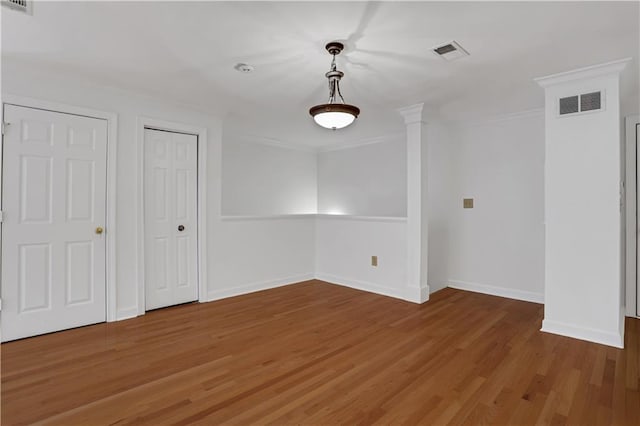 spare room featuring ornamental molding, visible vents, baseboards, and light wood-style floors
