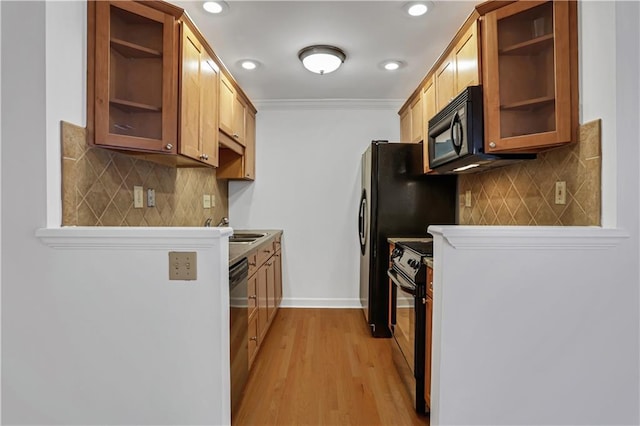 kitchen featuring glass insert cabinets, open shelves, decorative backsplash, light wood finished floors, and black appliances