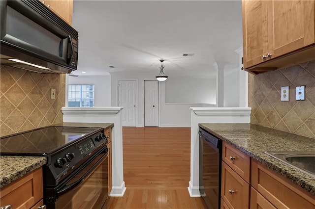 kitchen with brown cabinetry, tasteful backsplash, light wood-style flooring, black appliances, and baseboards
