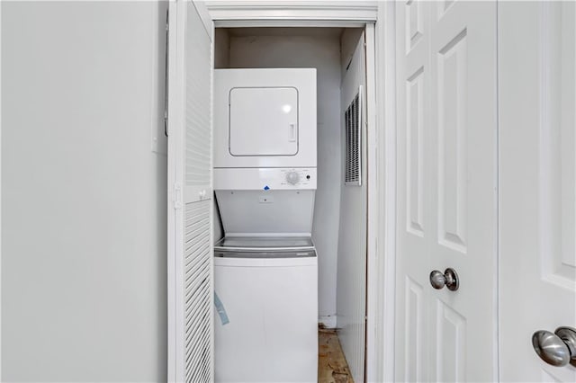 clothes washing area with stacked washing maching and dryer and laundry area