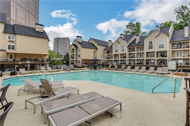 pool with a residential view, a patio area, and fence