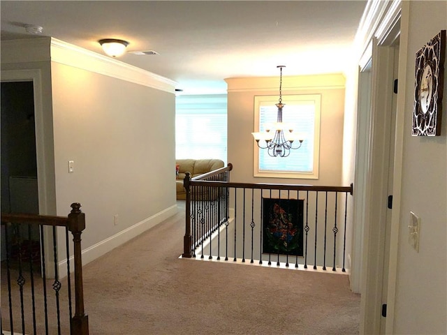 corridor with ornamental molding, light colored carpet, an upstairs landing, and an inviting chandelier