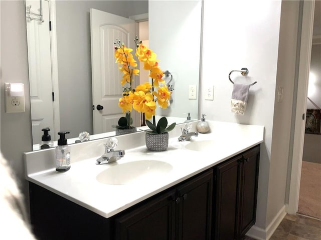 full bathroom featuring a sink, baseboards, and double vanity