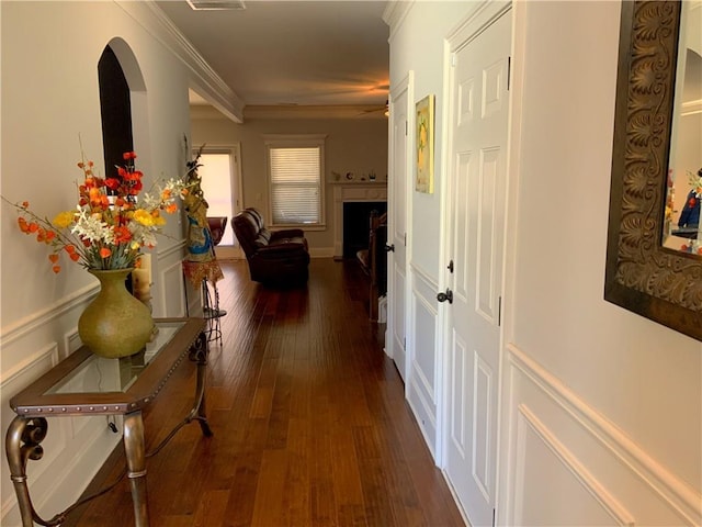 corridor with ornamental molding, visible vents, and dark wood finished floors