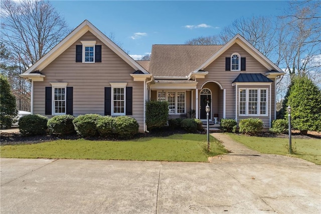 view of front facade featuring a shingled roof and a front yard