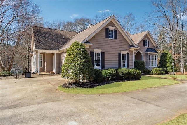 traditional home with a front lawn, concrete driveway, and roof with shingles