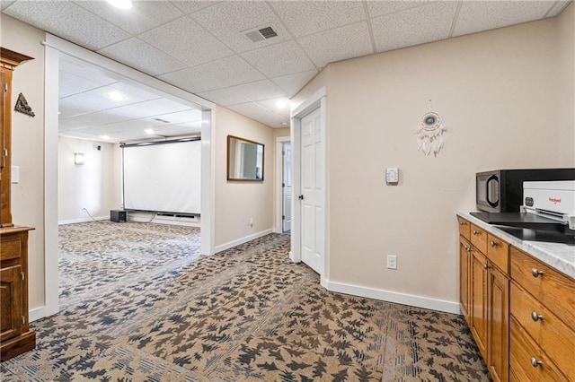 kitchen with visible vents, baseboards, light countertops, brown cabinets, and dark colored carpet