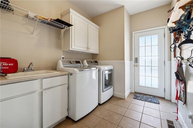 laundry room featuring a wainscoted wall, separate washer and dryer, a sink, visible vents, and cabinet space