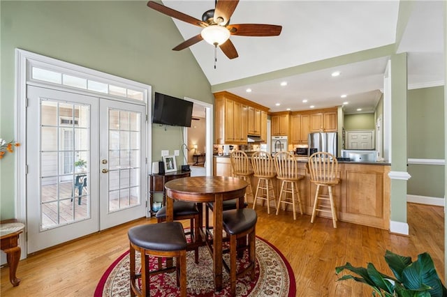 dining area featuring high vaulted ceiling, french doors, light wood-style flooring, and baseboards