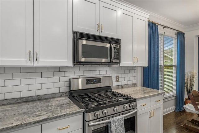 kitchen with dark wood-type flooring, tasteful backsplash, white cabinetry, stainless steel appliances, and crown molding