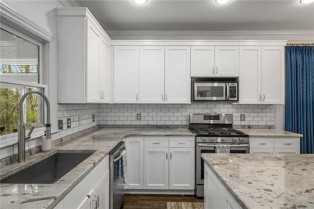 kitchen with a sink, tasteful backsplash, white cabinetry, and stainless steel appliances