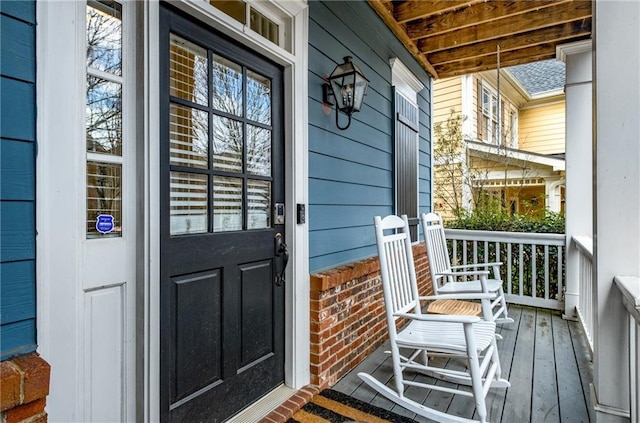 view of exterior entry featuring brick siding and a porch