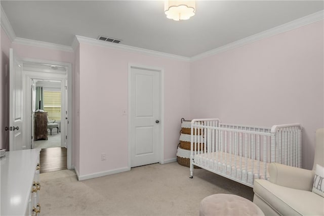 carpeted bedroom with visible vents, baseboards, a crib, and crown molding