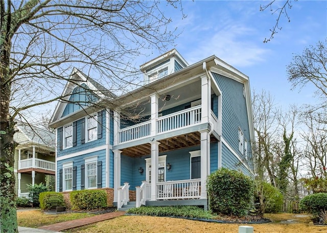 view of front of house featuring brick siding, a porch, and a balcony