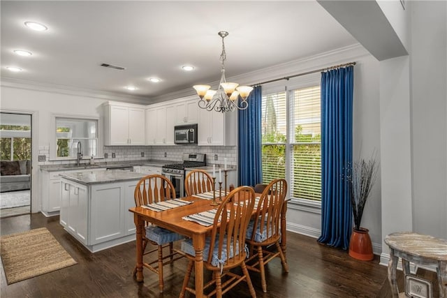 dining space featuring visible vents, baseboards, dark wood finished floors, ornamental molding, and a notable chandelier