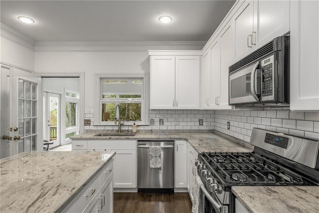 kitchen featuring ornamental molding, a sink, white cabinets, appliances with stainless steel finishes, and backsplash