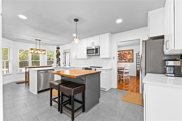 kitchen with a peninsula, backsplash, white cabinets, and stainless steel appliances