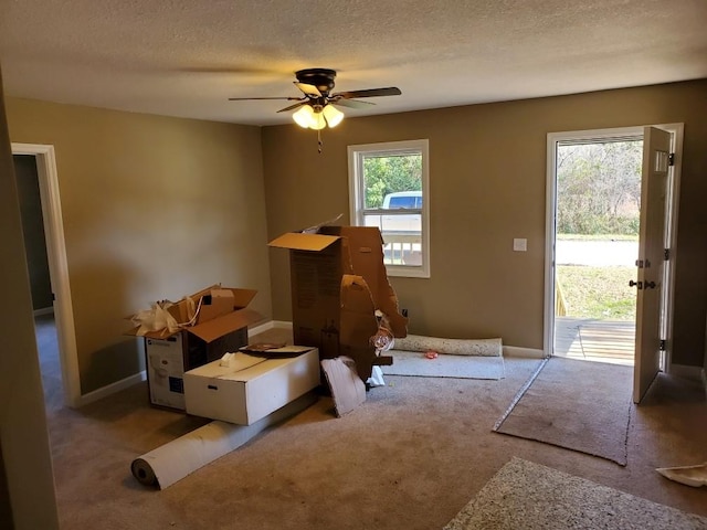 misc room featuring light carpet, ceiling fan, and a textured ceiling