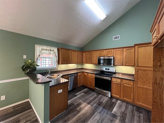 kitchen featuring stainless steel appliances, a peninsula, a textured ceiling, dark countertops, and visible vents