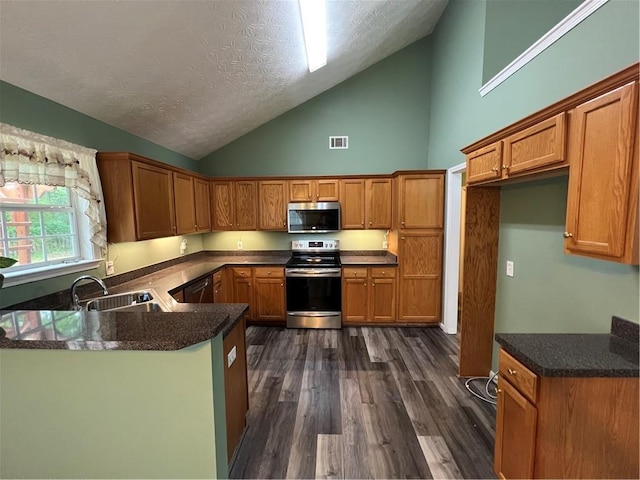 kitchen with brown cabinets, dark wood finished floors, stainless steel appliances, visible vents, and a sink