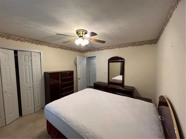 bedroom with multiple closets, light colored carpet, and ceiling fan