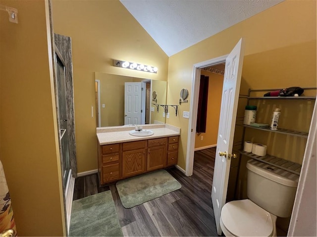 full bathroom featuring vaulted ceiling, wood finished floors, vanity, toilet, and a walk in shower